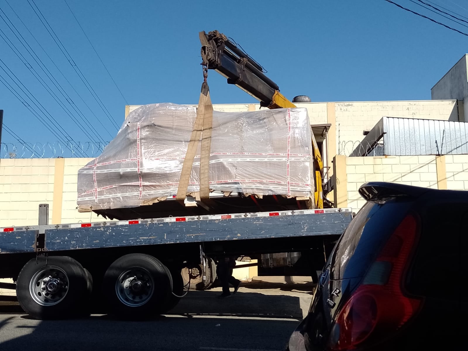 Guindaste içando uma carga embalada para cima da prancha de um caminhão da A&G